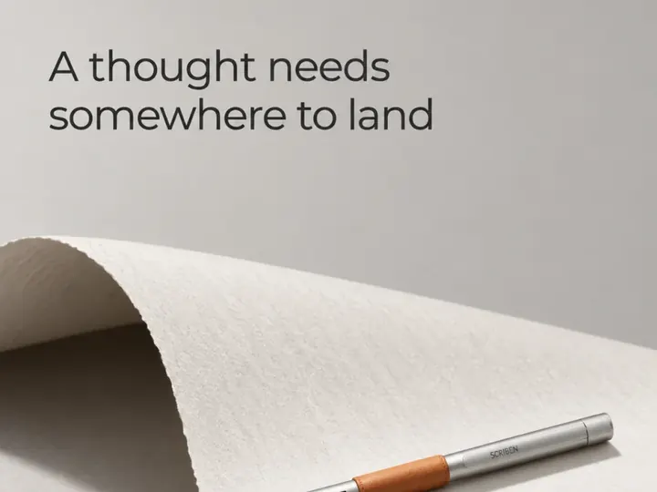 A thought needs somewhere to land. A pen on a curl of paper.