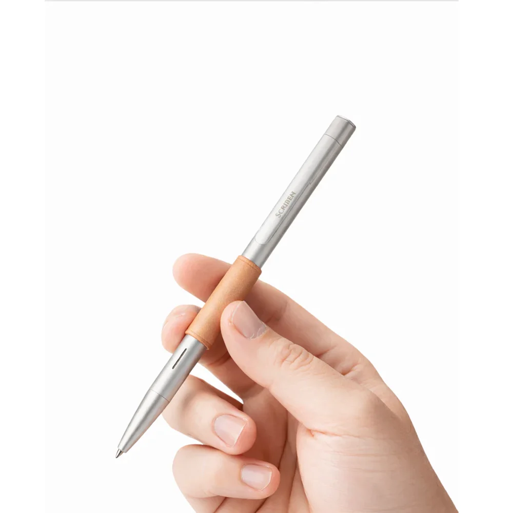 The Scriben pen held in the hand at writing angle, showing its size against the fingers